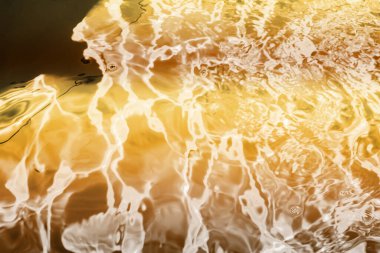 Blurred transparent Yellow Gold colour clear calm water surface texture with splashes and bubbles. Trendy abstract nature background. Water waves in sunlight. water background, oil