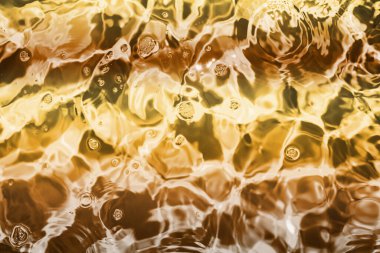 Blurred transparent Yellow Gold colour clear calm water surface texture with splashes and bubbles. Trendy abstract nature background. Water waves in sunlight. water background, oil