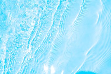 Bulanık mavi, berrak, durgun su yüzeyi dokusu sıçrama ve kabarcıklarla kaplı. Moda soyut doğa geçmişi. Güneş ışığında su dalgaları. su arkaplanı