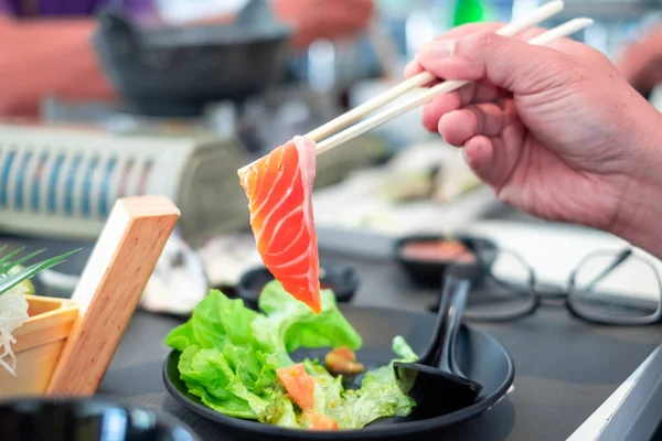 Stock image Eating salmon,Asian people eating sashimi set in Asian restaurant. Hirame sashimi,salmon sashimi and tuna sashimi dish. Japanese food concept