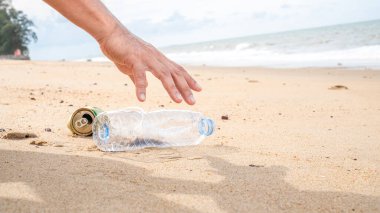 Plajda plastik şişe temizliği yapan bir el. Dünya konseptini kurtar. Çevre, ekoloji bakımı, yenilenebilir konsept, doğa koruma turizmi