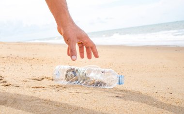 Plajda plastik şişe temizliği yapan bir el. Dünya konseptini kurtar. Çevre, ekoloji bakımı, yenilenebilir konsept, doğa koruma turizmi
