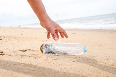 Plajda plastik şişe temizliği yapan bir el. Dünya konseptini kurtar. Çevre, ekoloji bakımı, yenilenebilir konsept, doğa koruma turizmi