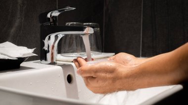 Adamın eli evdeki lüks tuvaletlerden birinde lavaboya dökülüyor..