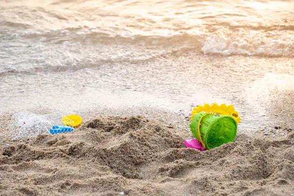 children\'s sand play equipment Placed on the sand, trash on the sand, caring for the environment around the sea