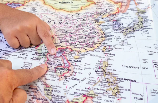 Tourist\'s hand pointing at world map of Thailand. Located in Southeast Asia, Thailand is a cultural capital of global interest and a destination. top view