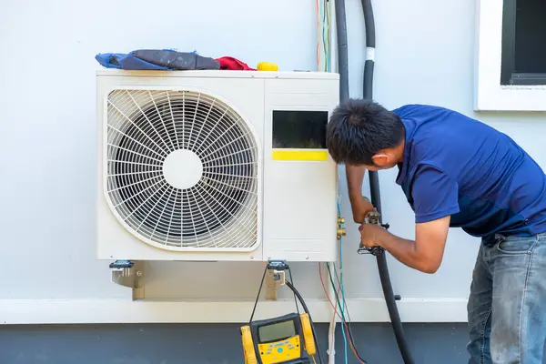 Male technician installing outdoor unit of air conditioner  to cool the household in the summer. air compressor, electronic,