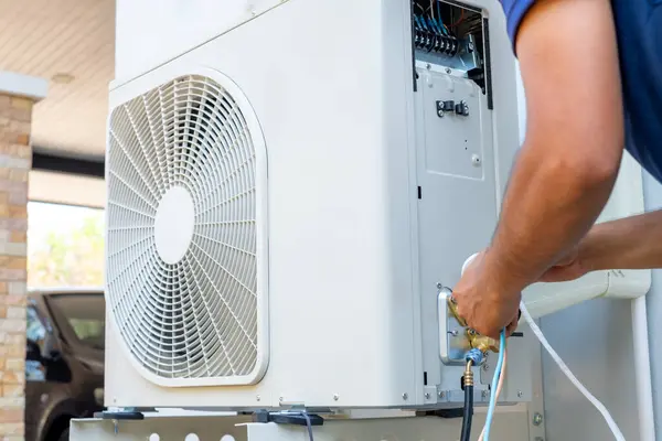 Erkek teknisyen yazın evi serinletmek için açık hava kliması kuruyor. Hava kompresörü, elektronik, sıcak yaz, yüksek sıcaklık, tropikal ülkeler