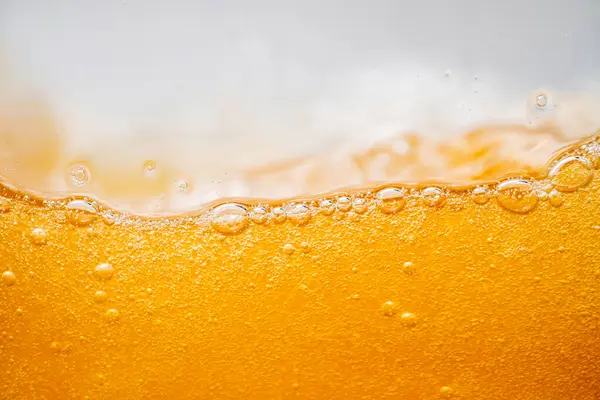 Parlak portakal yağını veya birayı kapat doku ve doğa dalgaları, güzel dalgalar eğrisi ve grafik tasarım ve arka plan için pürüzsüz küçük kabarcıklar, yağlı baloncuklar, yumuşak bira kabarcıkları, seçici odaklanma