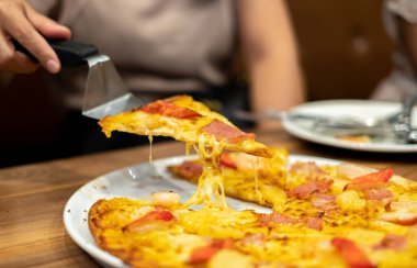 Eritilmiş peynirli sıcak Hawaii pizzası servis ediliyor. Yemek reklamları, menüler, restoranlar ve lezzetli, taze ve günlük yemek konseptleri için idealdir.