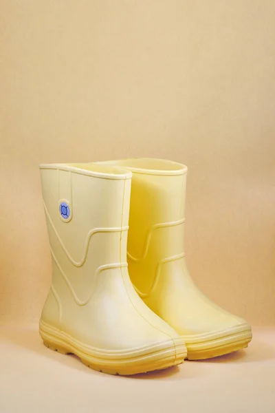 Yellow rubber boots on yellow background. Kids shoes. Full depth of field. Closeup