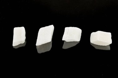 Kesik küp hindistan cevizi, siyah arka planda izole edilmiş. Tatlı kurutulmuş hindistan cevizi küpleri. Kapat.