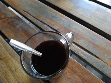 black coffee in a glass cup with a spoon