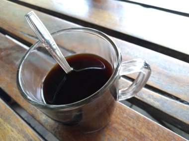 black coffee in a glass cup with a spoon