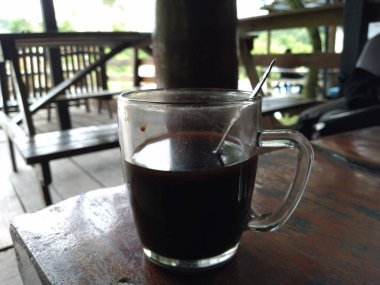 black coffee in a glass cup with a spoon