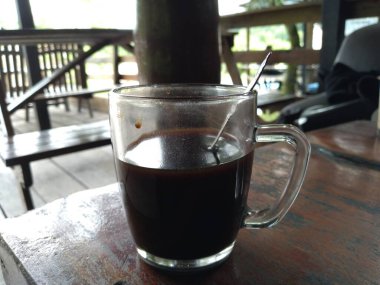 black coffee in a glass cup with a spoon