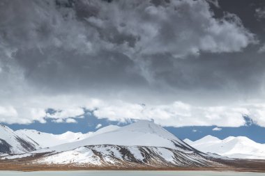 Dağlardaki kar dağı. Güzel gökyüzünün arka planındaki bulutlar