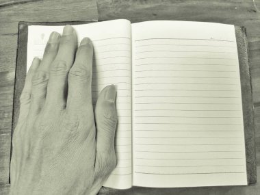 Ellerini kitapçığın üzerine koy. Siyah beyaz fotoğraf. Yaşlı adam eli..