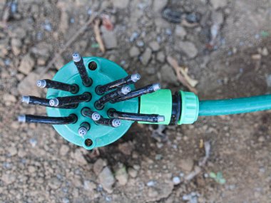 Bahçeye su püskürtmek için kullanılan yeşil hortumlu yeşil bir fıskiye.