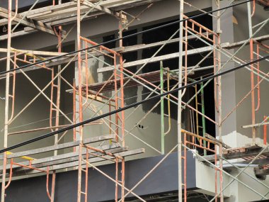 Bir fotoğraf, önünde yığılmış bir sürü iskelesi olan inşaat halindeki bir evi gösteriyor..