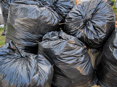 Siyah plastik poşetlerin içinde kurumuş otların fotoğrafı.