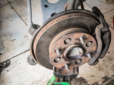 Rutin bakım gerektiren bir arabanın yakınındaki bir disk freninin fotoğrafı.