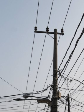 Dik kutuplar elektrik kabloları, internet bağlantıları ve açık mavi gökyüzünün arka planına karşı sokak ışıkları yerleştirmek için kullanılır..