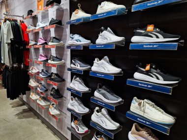 Surabaya-29 Haziran 2023: Reebok spor ayakkabıları ve satılık bazı giysiler bir alışveriş merkezindeki siyah arka planda gösteriliyor ve bazıları satılık..