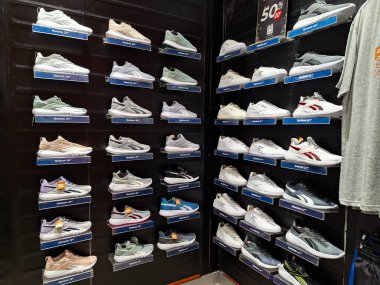 Surabaya-29 Haziran 2023: Reebok spor ayakkabıları ve satılık bazı giysiler bir alışveriş merkezindeki siyah arka planda gösteriliyor ve bazıları satılık..
