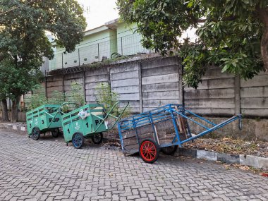 Surabaya-June 27, 2023: Garbage carts and trash cans are green and blue, and both are used as tools to clean up the environment. clipart