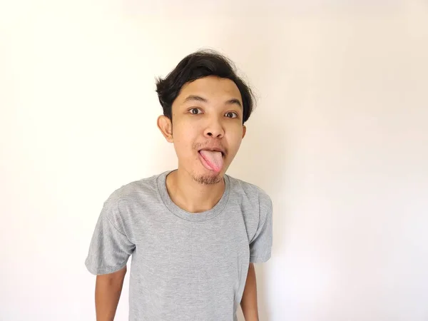 アジア人男性の面白いいじめやいじめの顔 白に隔離された舌を突き出す — ストック写真