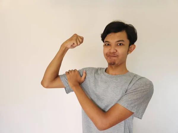 Возбужденный Азиат Серой Рубашке Показывает Сильный Жест Поднимая Руки Мускулы — стоковое фото