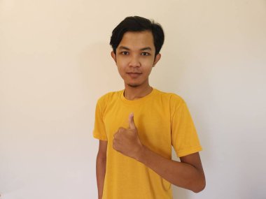 Mutlu Asyalı adam beyaz arka planda iyi bir el işareti olarak baş parmağını gösteriyor..