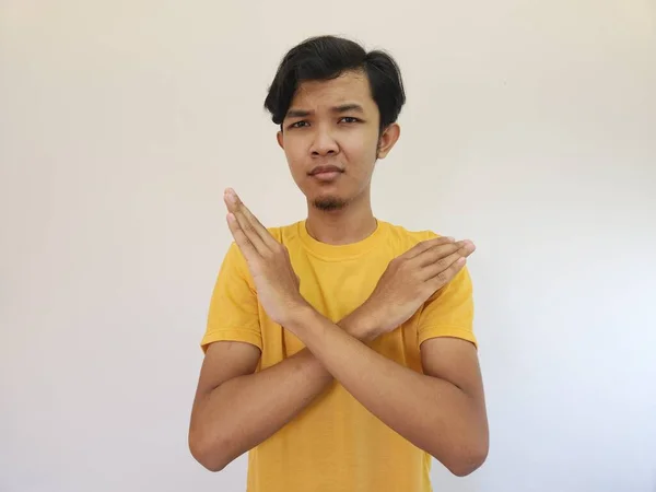 若いハンサムなアジア人男性の肖像画は 負の記号 怒りの顔 隔離された青の色の背景を行う腕を横断停止または拒否式を示す — ストック写真