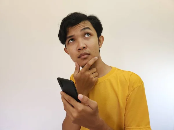 Asiatisk Man Håller Mobiltelefon Tittar Upp Kopiera Utrymme — Stockfoto