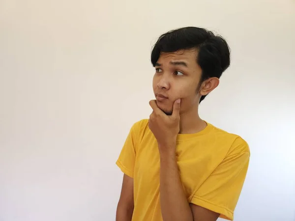 アジア系の男で思考ジェスチャー コピースペース 黄色いシャツ — ストック写真