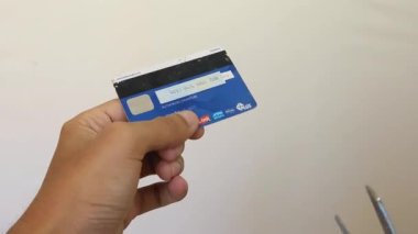 Adam kredi kartını makasla kesiyor.