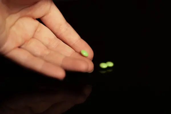 Close Hand Handing Green Pill — стоковое фото