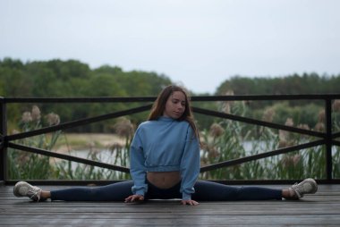 Bulutlu ve yağmurlu bir havada parkta ayrılan bir kız görülüyor.