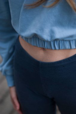 Parkta yağmurlu bir havada, spor takım elbiseli bir kızın atletik vücudunu kapatın. 