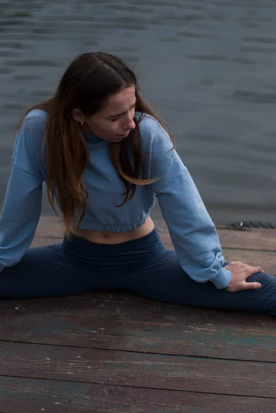 Young girl is doing yoga near  lake