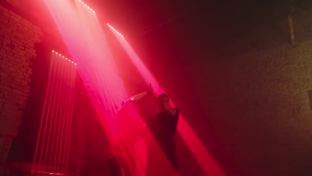 从下面跳着舞的拉美交际舞的人中 有一对跳探戈舞的舞伴向镜头方向旋转 在阁楼上跳舞的长长的碎片 移动着红色的激光束 同步腿和胳膊摆动 螺旋体 — 图库视频影像