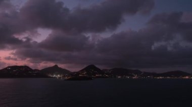 Gece limanı, alacakaranlık silueti ve gün batımından sonra şehir manzarasının akşam manzarası üzerindeki karanlık gökyüzünün arka planındaki St. Martin adasının silueti, deniz yolculuğunun izleri.