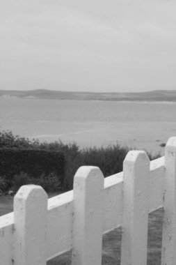 Beyaz ahşap haç, bulutlu havayla çitin üstünde