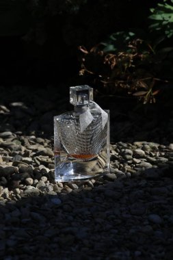 perfume bottle in a glass with water drops and a black background.