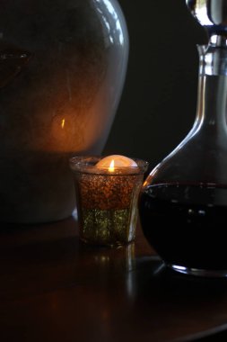 Karanlık bir arka planda bir bardak şarap ve mum.