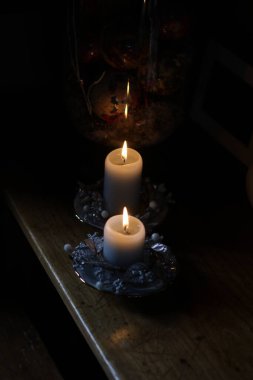 Karanlık bir arka planda, bir bardakta yanan mum.