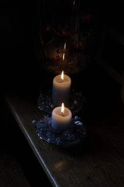 close up of a burning candle on a black background, candles and a bottle