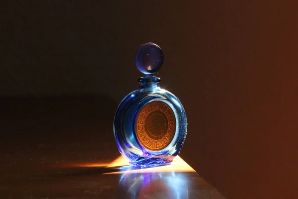 Uma Garrafa Perfume Com Luz Sobre Uma Superfície Madeira — Fotografia de Stock