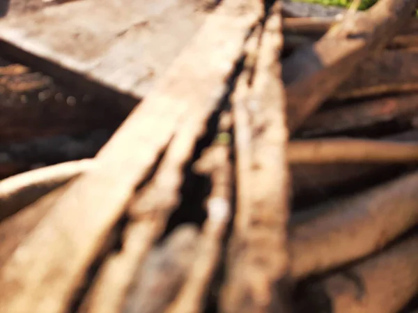 Blurred or unfocused or defocused Pile or stack of brown wood on a sunny day